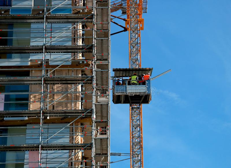 workers-elevator-climb-to-unfinished-building-next-which-scaffolding-stands-construction-site-104871297.jpg